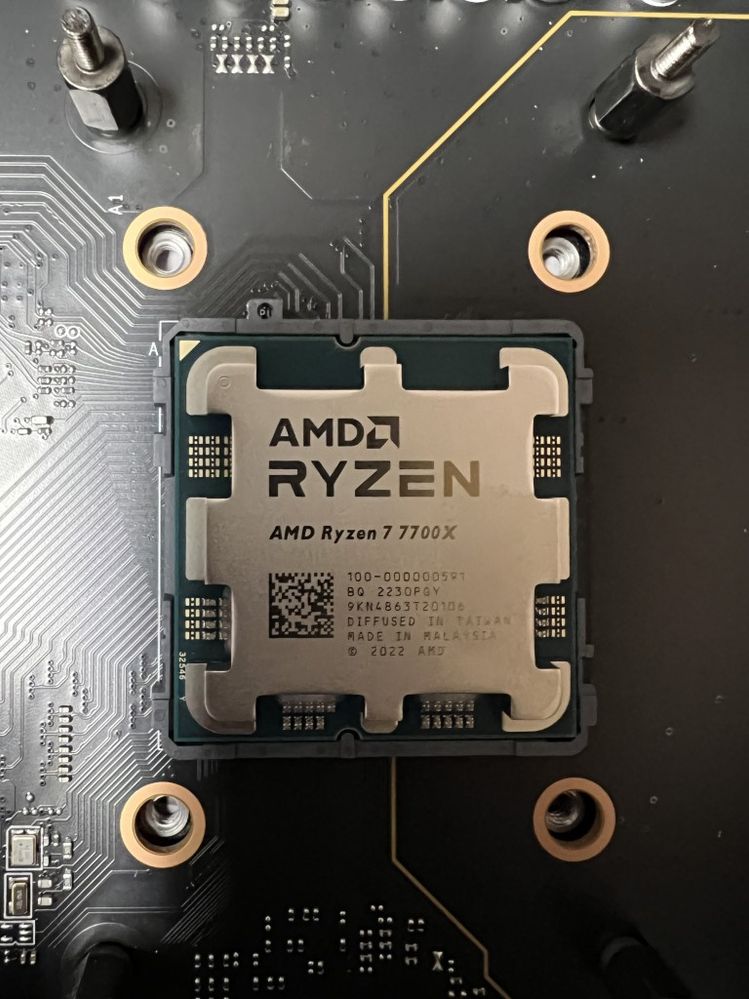 The AMD 7700X CPU is in the socket, and the clamping mechanism has been removed carefully.