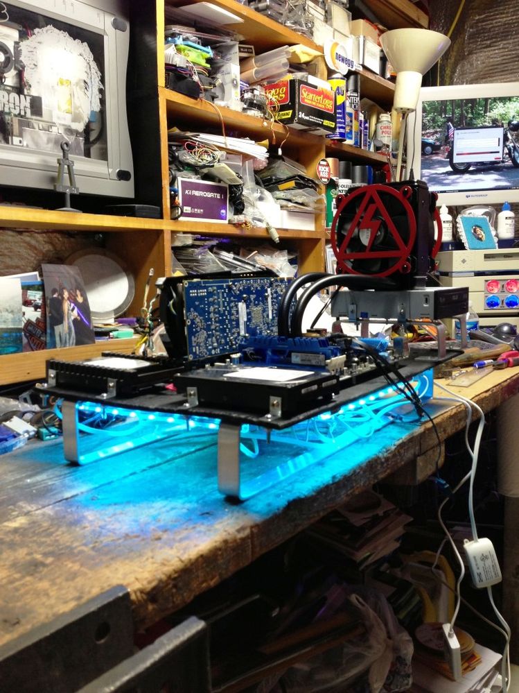Aluminum bars hold the motherboard, which is mounted to plywood.